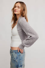 Free People Opal Shrug in Grey Flannel — chunky knit open-front shrug with balloon sleeves, worn over a white crop top with jeans.