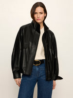 Sanctuary Alana Jacket in black faux leather, oversized fit with stand collar, worn open over cream sweater and blue jeans, front view