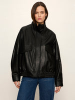 Sanctuary Alana Jacket in black faux leather with bomber silhouette, front zip, chest pockets, and elastic hem, worn by a model with blue jeans