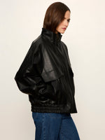 Sanctuary Alana Jacket in black faux leather with oversized fit, chest flap pocket, funnel neck, and elasticated hem, side view on model
