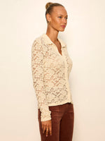 Sanctuary Dreamer Lace Shirt in bone, side view on model — sheer floral lace, long sleeves, collared V-neck, paired with rust trousers.