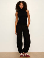 Sanctuary Micro Balloon Pant in black, front view on model paired with sleeveless turtleneck and burgundy sneakers