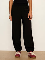 Sanctuary Micro Balloon Pant in black, front view on model, featuring elasticated waist and gathered ankle cuffs, styled with burgundy sneakers.
