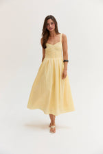 Crescent Valerie Bustier Fit And Flare Dress in light yellow, front view on model, featuring sweetheart neckline, wide straps, and pleated midi skirt.