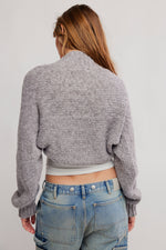 Free People Opal Shrug in Grey Flannel, back view on model, chunky knit crop with mock neck and long sleeves, paired with jeans.