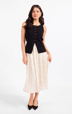 Sadie Margaux Sweater Waistcoat in black, button-front sleeveless knit vest worn by model with polka dot pleated skirt, front view
