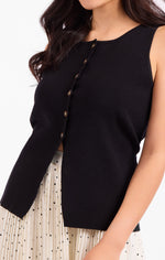 Sadie Margaux Sweater Waistcoat in black, sleeveless with diagonal bronze button detail, worn over a cream polka dot skirt