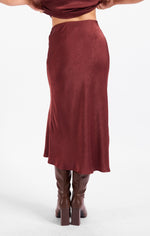 Sadie Ceremony Midi Skirt in dark wine satin jacquard, back view on model styled with matching knee-high brown boots