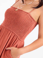 Sadie and Sage Sugarloaf Stripe Jumpsuit in Mahogany, close-up of smocked bodice with thin stripe skirt and spaghetti straps on model.