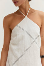 Crescent Lena Linen Contrast Stitch Halter Mini Dress in white, close-up front view on model showing diagonal dark stitching detail