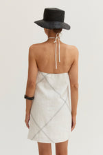 Crescent Lena Linen Contrast Stitch Halter Mini Dress in White, back view on model with black wide-brim hat