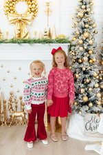 Mila Candy Canes Sweater in pink with candy cane print, worn by a girl paired with a red skirt, holiday setting