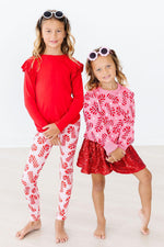 Mila Candy Canes Sweater in pink with red candy cane print, worn by a young girl with a red sequin skirt