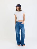 Daze Denim 2K Mid Rise Relaxed Baggy jeans in medium blue wash, worn by model with white crop top and navy cap, front view