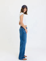 Daze Denim 2K Mid Rise Relaxed Baggy jeans in Vesper medium blue wash, side view on model with white crop top and navy cap