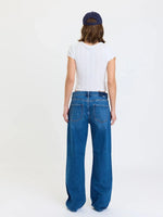 Daze Denim 2K Mid Rise Relaxed Baggy jeans in Vesper medium blue wash, back view on model with white crop tee and navy cap