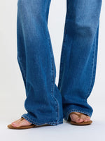 Daze Denim 2K Mid Rise Relaxed Baggy jeans in medium blue wash, close-up of wide-leg hem pooling over tan thong sandals