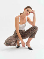 Daze Denim Westward Barrel Leg jeans in Cool Cool Cat leopard print worn by model crouching in white tank top and black heels