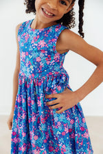 Young girl wearing Mila & Rose Tank Twirl Dress in blue floral print with pink, purple, and teal flowers
