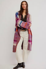 Free People Enid Cardi in Ocean Sunset Combo, long multicolor striped knit cardigan worn open over black top and white jeans.