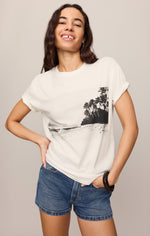 Z SUPPLY La Playa Boyfriend Tee in Sea Salt — white relaxed-fit tee with black beach palm tree graphic, worn by smiling model with denim shorts.