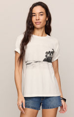 Z SUPPLY La Playa Boyfriend Tee in Sea Salt — front view on model, white tee with black tropical beach photo print, paired with denim shorts