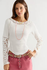 Free People Amber Lace Cuff top in white, ribbed fabric with floral lace sleeve panels and neckline trim, worn by model with pink jeans