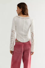 Free People Amber Lace Cuff top in white, back view on model, featuring ribbed knit body with floral lace sleeves and neckline trim.