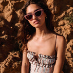 I SEA Lola sunglasses in Dusty Rose with plum polarized lenses, cat-eye frame, worn by model outdoors against sandstone rocks.