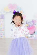 Mila Never Miss A Beat L/S Tutu Dress in lavender tulle with heart print bodice, worn by young girl with purple bow hair clip