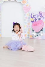 Mila Never Miss A Beat L/S Tutu Dress in white with heart print and purple tutu skirt, worn by toddler girl with pink toy phone