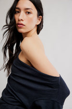 Free People Waterfall Cowl in Black worn off-shoulder by a model, showing draped cowl neckline and ribbed fabric texture.