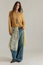 Opal Sweater in Sweet Potato — chunky golden-yellow crop knit sweater worn by model with wide-leg jeans and lace overlay, front view.