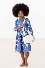 Mila Painted Skies 3/4 Sleeve Pocket Twirl Dress in blue unicorn print, worn by young girl holding a white mini purse