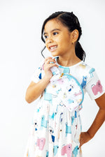 Mila Puppy Pals Belt Bag worn crossbody by a young girl in matching dog-print dress, white background lifestyle shot
