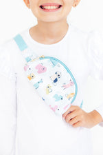 Mila Puppy Pals Belt Bag worn crossbody by a child, featuring colorful cartoon dog print on white with mint zipper and strap.