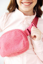 Mila Pink Fleece Belt Bag worn crossbody by smiling model in light pink zip-up jacket, close-up lifestyle shot