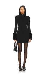 Steve Madden Riello Dress in black — fitted turtleneck mini dress with long sleeves and faux fur cuffs, worn with sheer tights