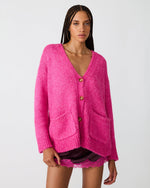 Steve Madden Finley Sweater in hot pink, oversized knit cardigan with V-neck, tortoise buttons, and front patch pockets, worn by model.
