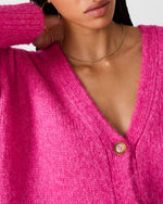 Steve Madden Finley Sweater in hot pink, close-up of model wearing V-neck knit cardigan with tortoise button and gold chain necklace