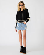 Steve Madden Dara Sweater in black with cream stripes, zip-up knit hoodie, worn by model with denim mini skirt and black wedge sneakers.