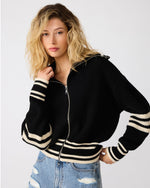 Steve Madden Dara Sweater in black with cream stripe trim, zip-front knit bomber style, worn by model with distressed jeans