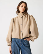 Steve Madden SA04169 TANN jacket in tan, featuring dramatic puff sleeves, mock neck, front button closure, and patch pockets, worn with blue jeans.