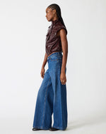 Steve Madden SC01142 cropped faux leather vest in Deep Fig dark burgundy, worn by model with wide-leg jeans, side view