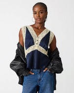 Steve Madden SC09035 navy satin cami top with cream lace trim and button detail, styled with blue jeans and black leather jacket on model.
