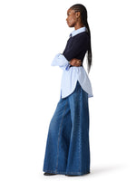 Steve Madden Lenny Knit Top in navy layered over light blue poplin shirt, worn with wide-leg jeans, side view on model.