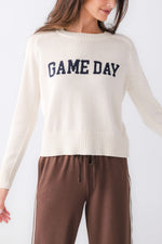 Z SUPPLY Varsity Stand In Sweater in cream/sandstone with navy 'GAME DAY' intarsia knit lettering, worn by model with brown track pants
