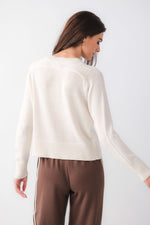 Z SUPPLY Varsity Stand In Sweater in Sandstone — back view on model, cream knit pullover with ribbed hem, cuffs, and crew neck, paired with brown track pants