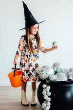 Mila Trick Or Twirl 3/4 Sleeve Pocket Twirl Dress in Halloween cat print, worn by girl in witch hat with candy bucket