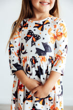 Mila Trick Or Twirl 3/4 Sleeve Twirl Dress on girl, white fabric with Halloween bows, cats, and stars print